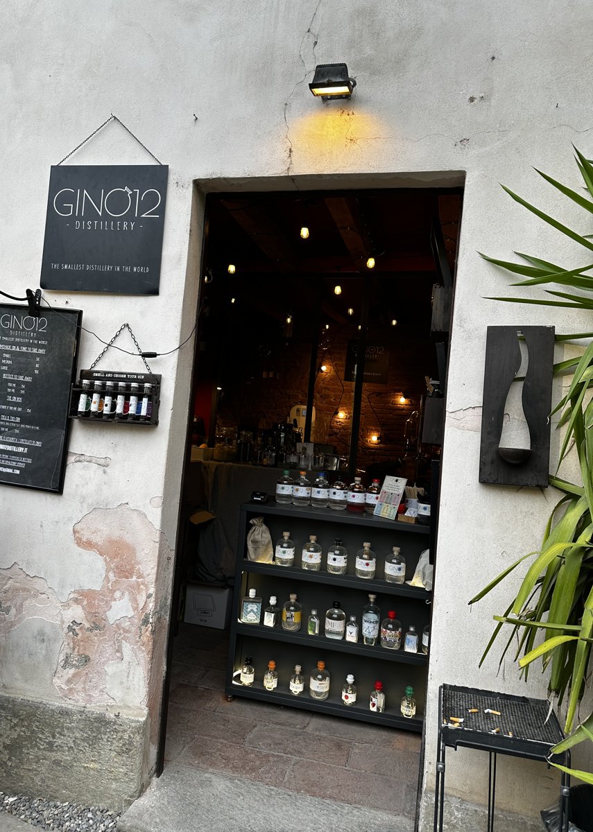GinO12の入口。白い壁に「GINO12 DISTILLERY」の看板が掛かり、奥にジンのボトル棚が見える