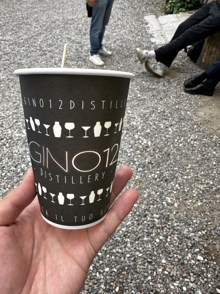 GinO12のロゴ入り紙コップに入ったジントニックを手に持つ